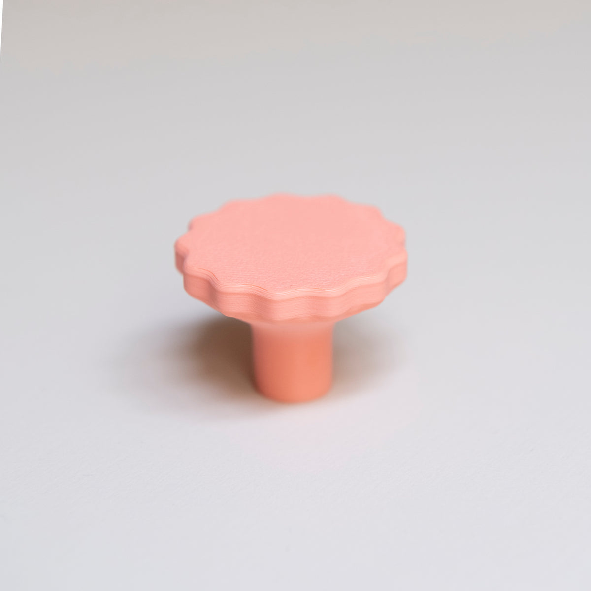 Bouton de meuble Manège couleur corail, créé en collaboration par Polycoco et Studio Couleur, en bioplastique éco-responsable.