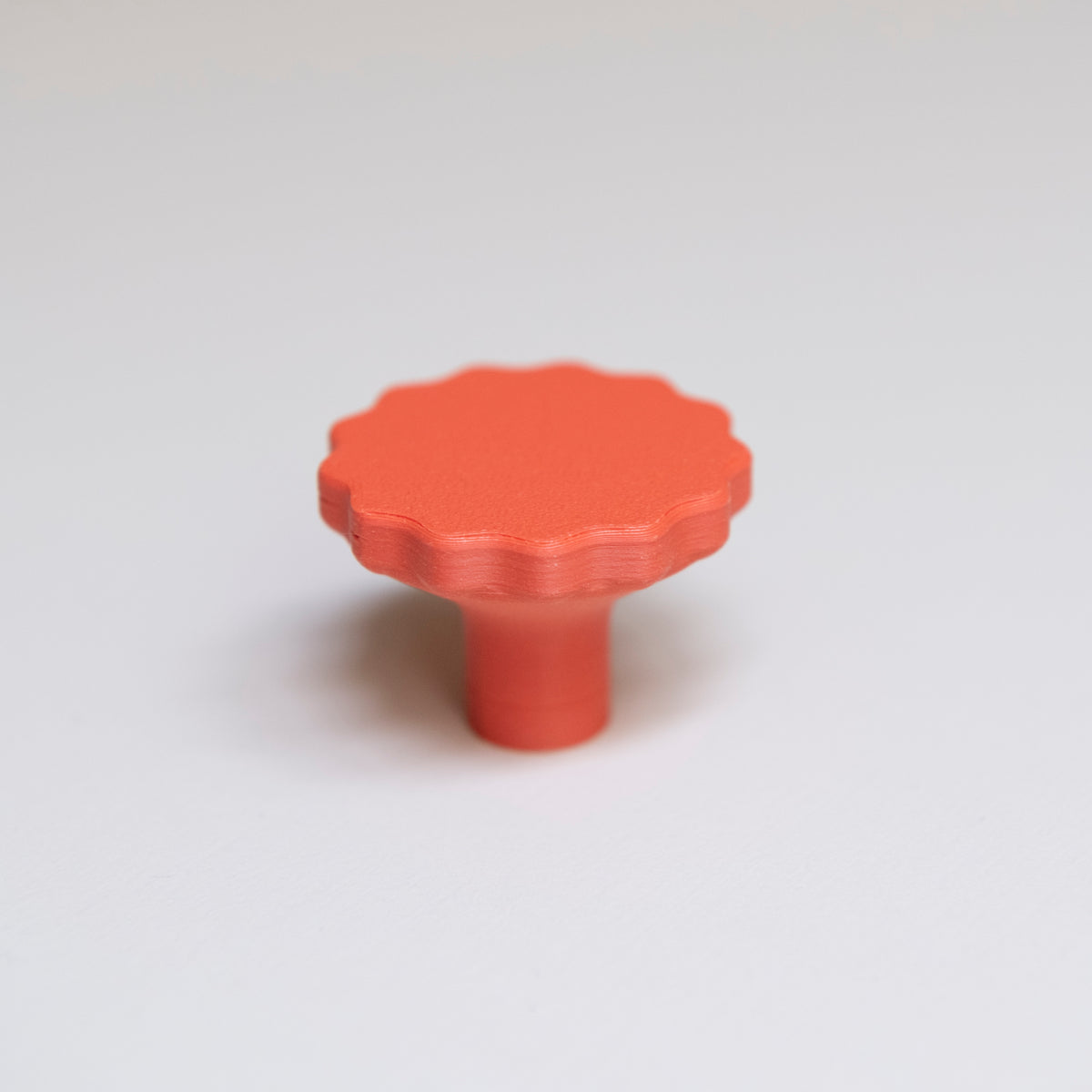 Bouton de meuble Manège couleur corail, créé en collaboration par Polycoco et Studio Couleur, en bioplastique éco-responsable.