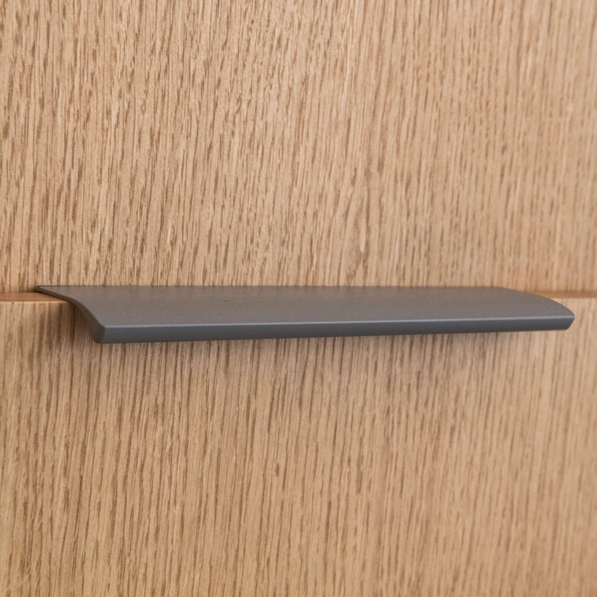 Poignée profilée pour meuble coloris taupe, de 20cm de longueur. Elle se fixe discrètement sur le rebord des portes de cuisine et d'armoires.