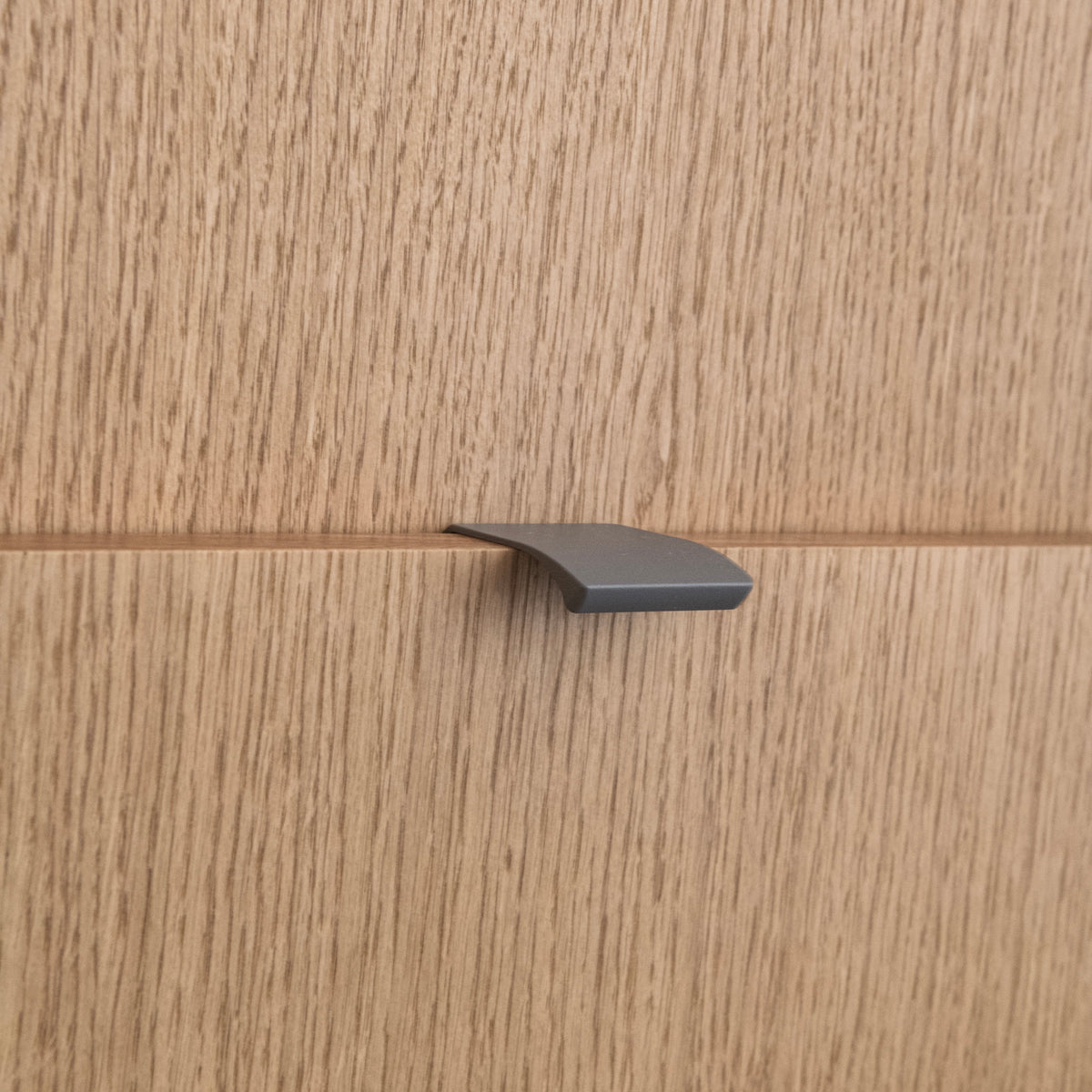Poignée profilée pour meuble coloris taupe, de 4cm de longueur. Elle se fixe discrètement sur le rebord des portes de cuisine.
