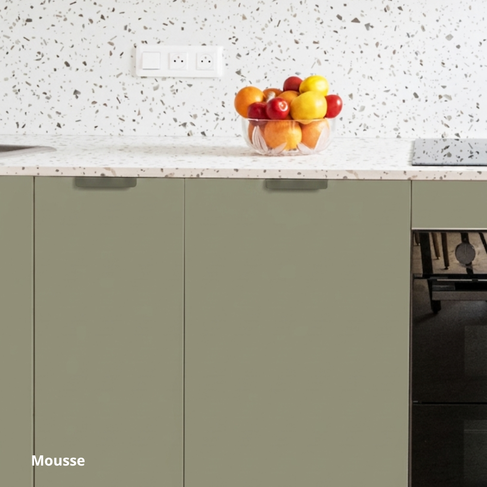Meubles bas de cuisine aux façades vert gris, plan de travail aspect terrazzo blanc et gris