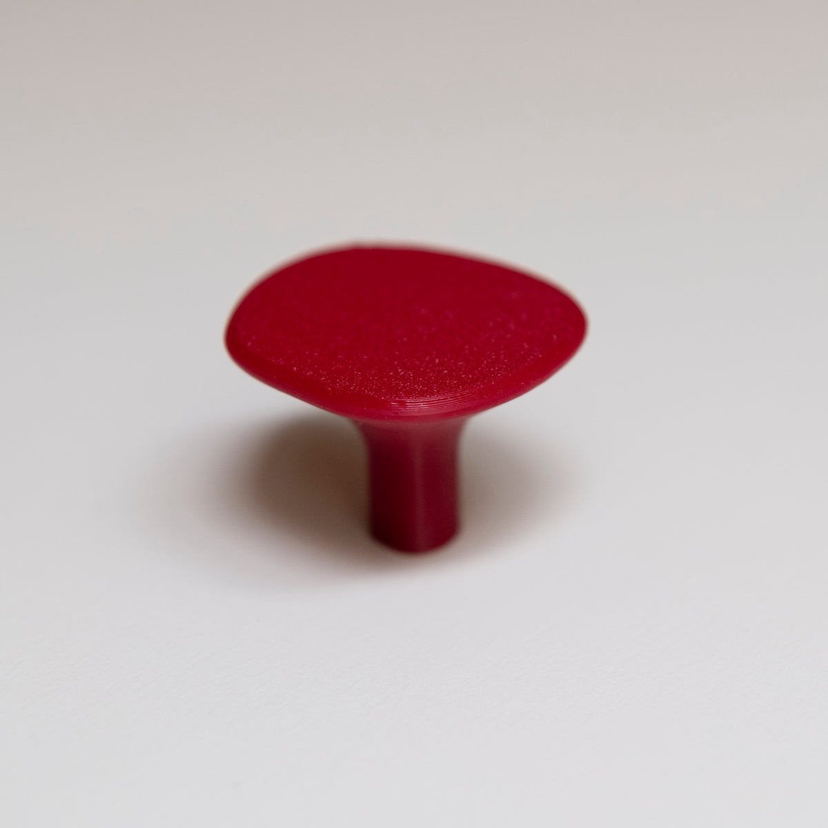 Bouton de meuble Galet rouge coloris Cerise, créé en collaboration entre Studio Couleur et Polycoco, en bioplastique éco-responsable. 
