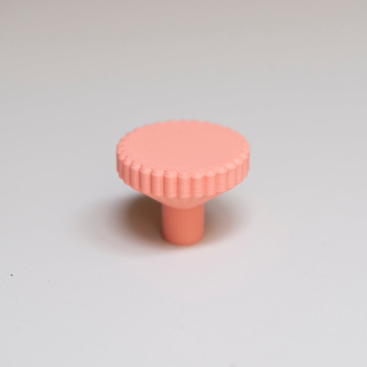 Bouton de meuble Biscuit couleur corail, créé en collaboration entre Studio Couleur et Polycoco, en bioplastique éco-responsable. 