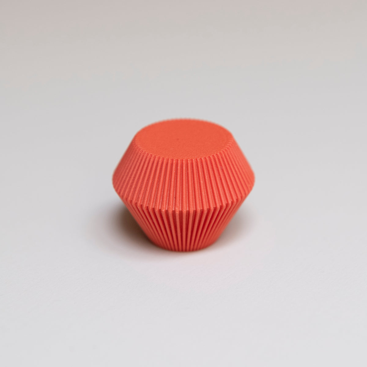 Bouton de meuble Facette couleur rouge-orangé, créé en collaboration entre Studio Couleur et Polycoco, en bioplastique éco-responsable. 