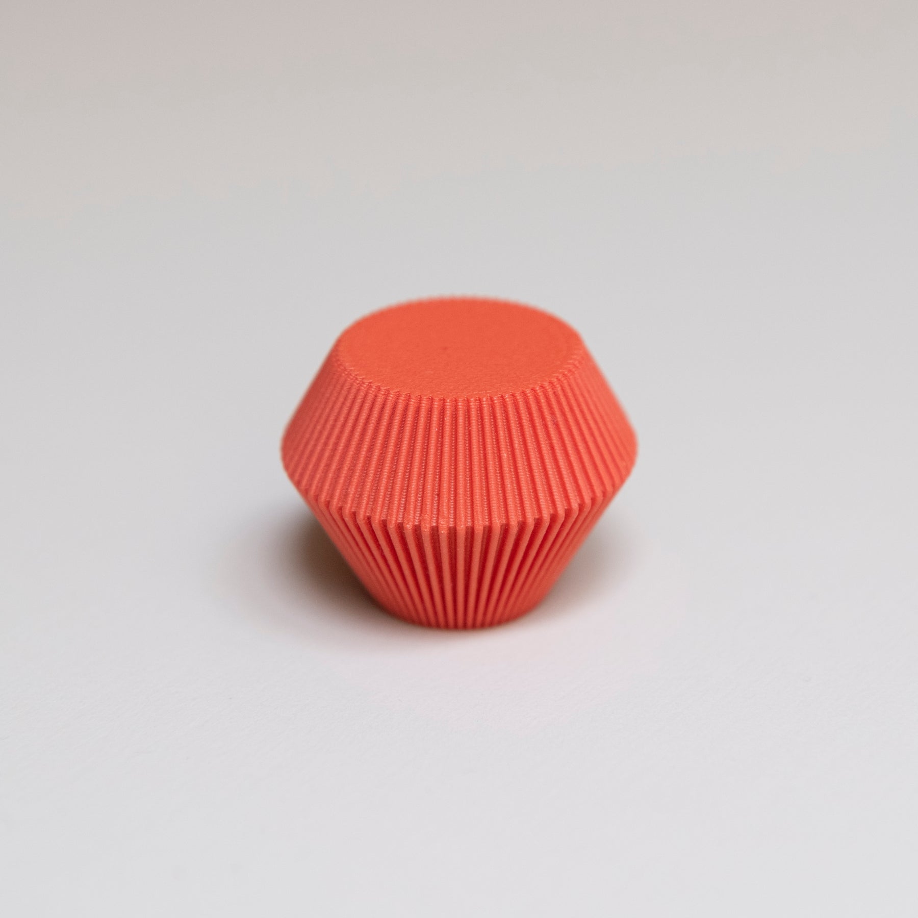 Bouton de meuble Facette couleur rouge-orangé, créé en collaboration entre Studio Couleur et Polycoco, en bioplastique éco-responsable. 