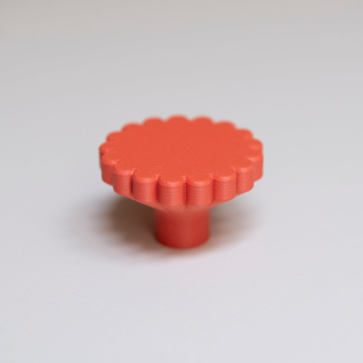 Bouton de meuble Marguerite couleur rouge-orangé, créé en collaboration entre Studio Couleur et Polycoco, en bioplastique éco-responsable. 