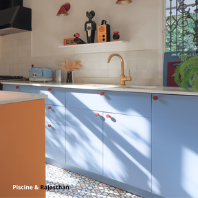 Cuisine linéaire aux portes bleues coloris "Tempête" Studio Couleur, posées sur des caissons Ikea Metod. Boutons de portes rouges et ilot central jaune-orangé coloris "Rajasthan".