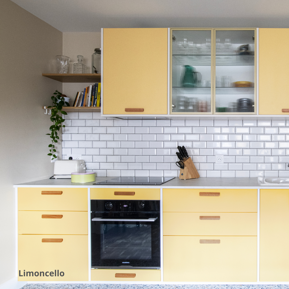 Cuisine aux portes et façades de tiroirs Studio Couleur jaunes, caissons Ikea Metod. Crédence en céramique et plan de travail blanc.