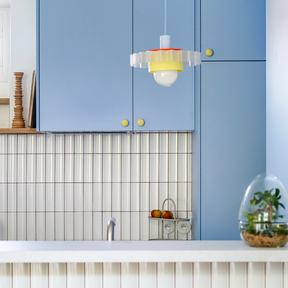 Cuisine Ikea Metod aux portes bleu clair coloris "Piscine" Studio Couleur, et boutons de porte jaune mat. Crédence en céramique et plan de travail blanc.
