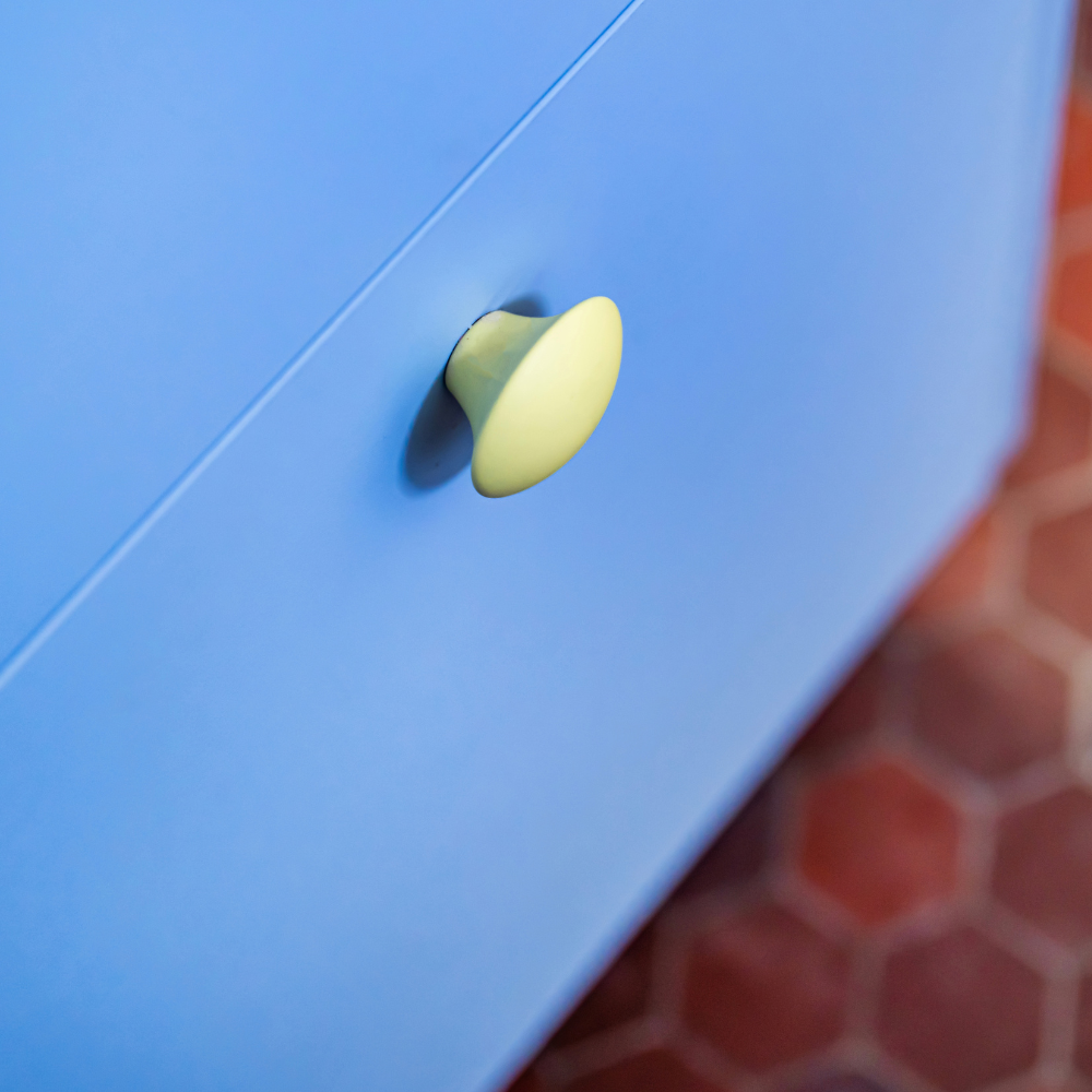 Bouton de meuble jaune mat sur porte bleue