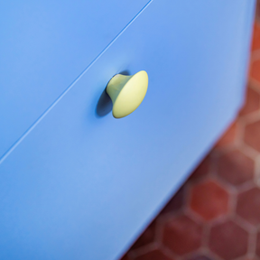 Bouton de meuble jaune mat sur porte bleue