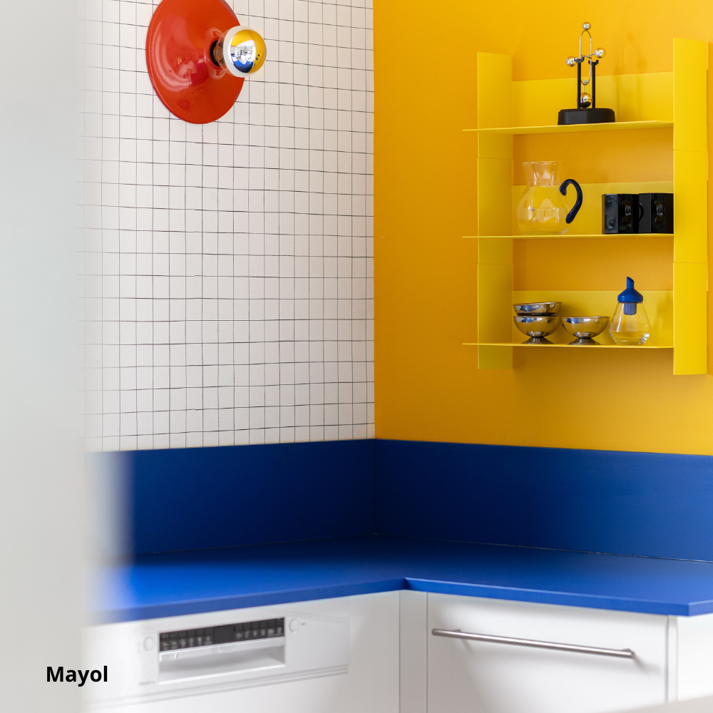 Plan de travail et crédence de cuisine sur-mesure bleu électrique coloris "Mayol" Studio Couleur. Meubles de cuisine blancs, murs et étagères jaunes, et applique rouge.