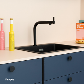 Plan de travail et crédence de cuisine rose, tiroirs de cuisine bleu marine et boutons de portes noirs