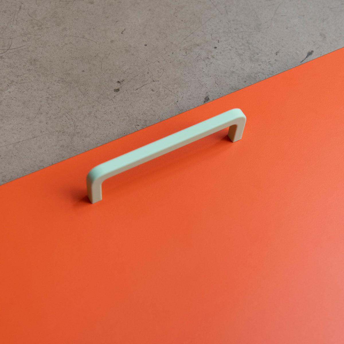 Poignée de meuble vert clair créée en collaboration par Polycoco et Studio Couleur, en bioplastique éco-responsable. Posée sur une façade de cuisine orange Studio Couleur pour caissons Ikea Metod.
