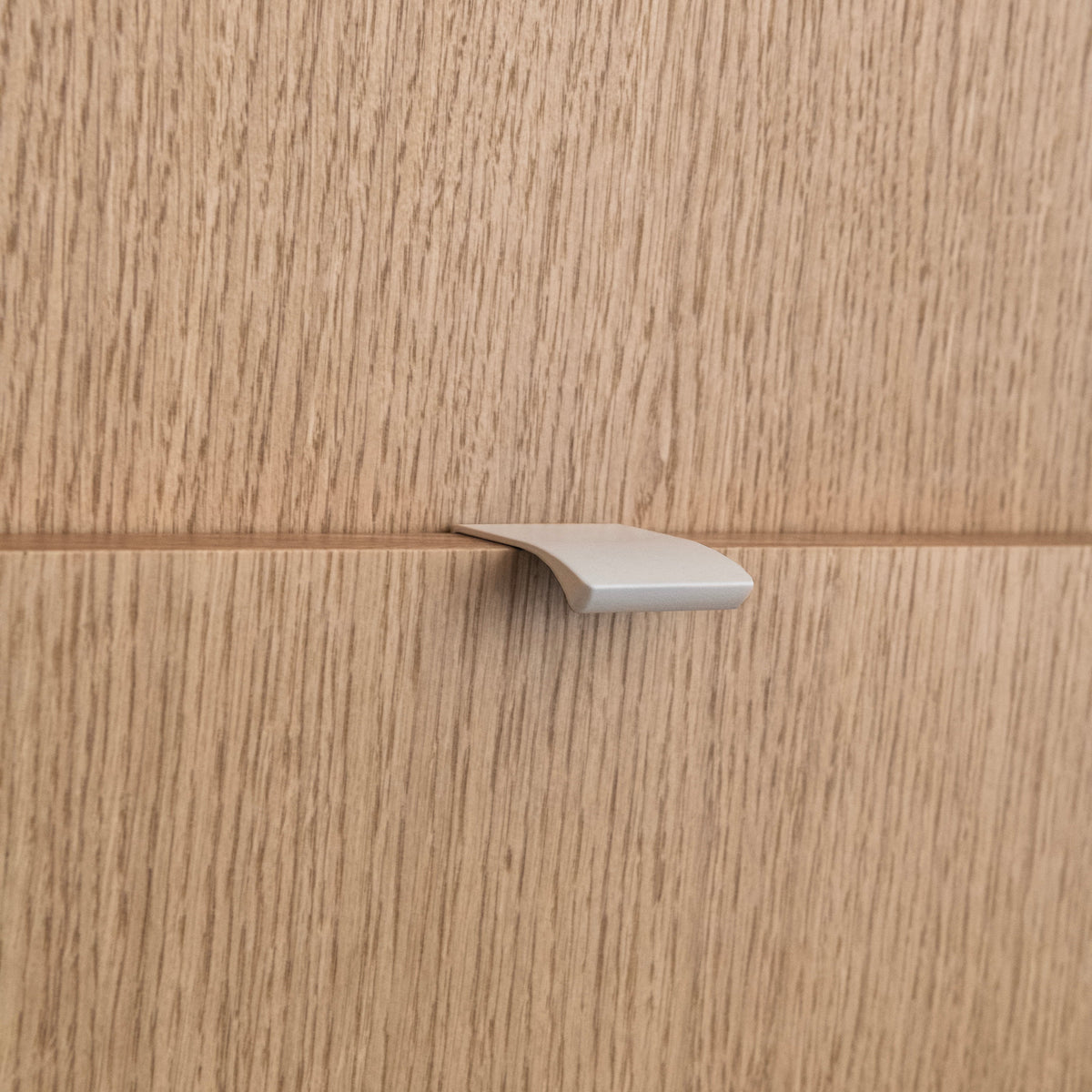 Poignée profilée pour meuble coloris beige, de 4cm de longueur. Elle se fixe discrètement sur le rebord des portes de cuisine.
