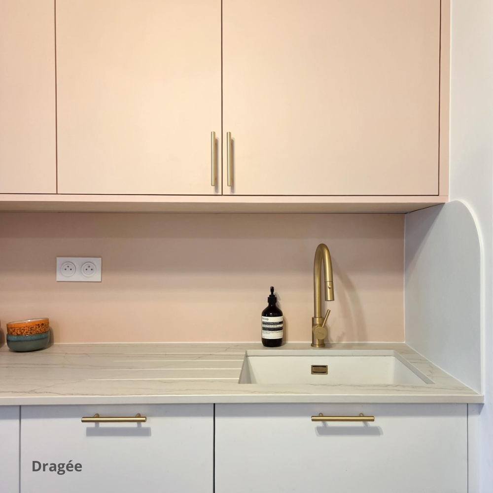 Meubles hauts de cuisine roses, avec poignées dorées, en retrait des meubles bas