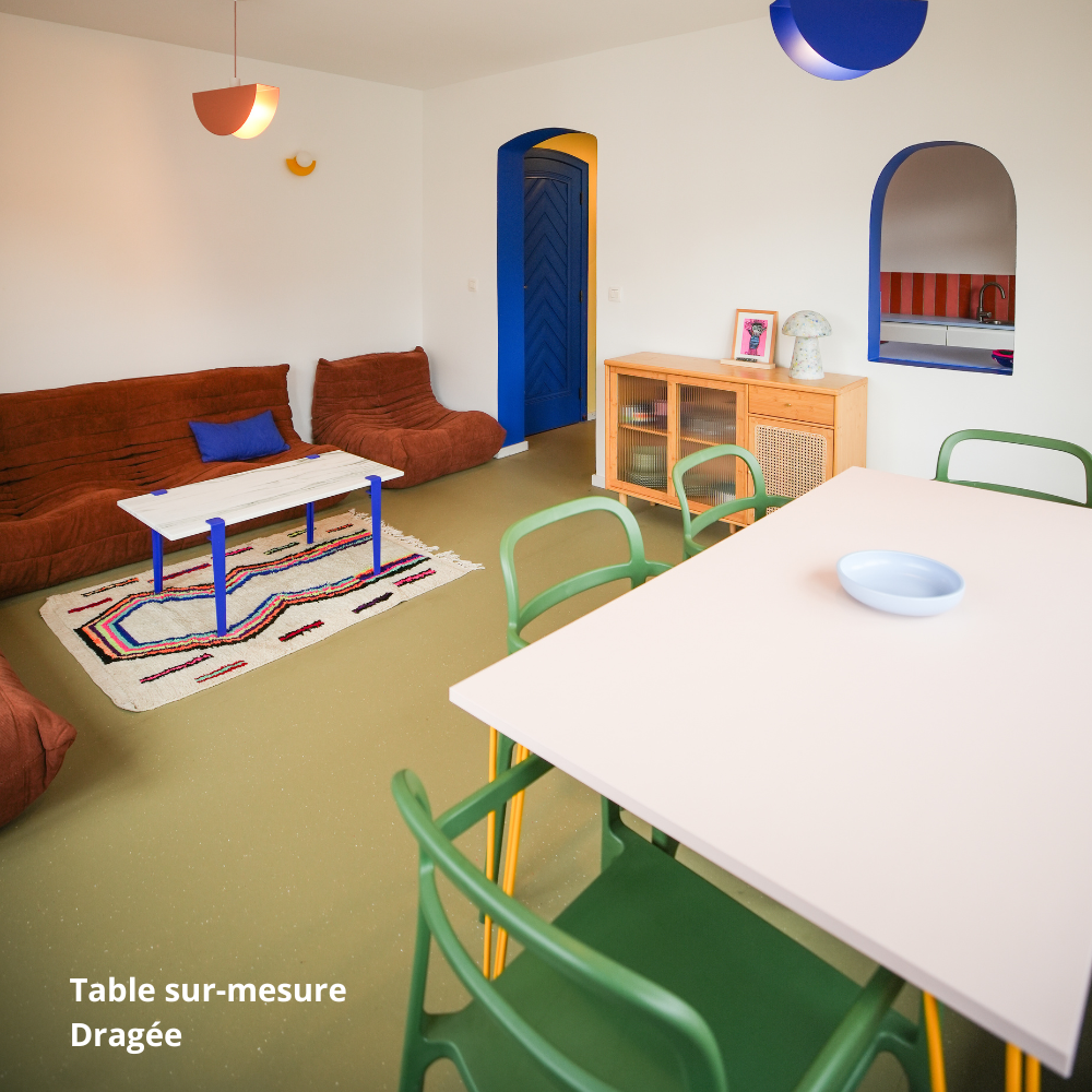 Table de salle à manger rose clair créée sur-mesure avec des panneaux Studio Couleur, et chaises vertes.