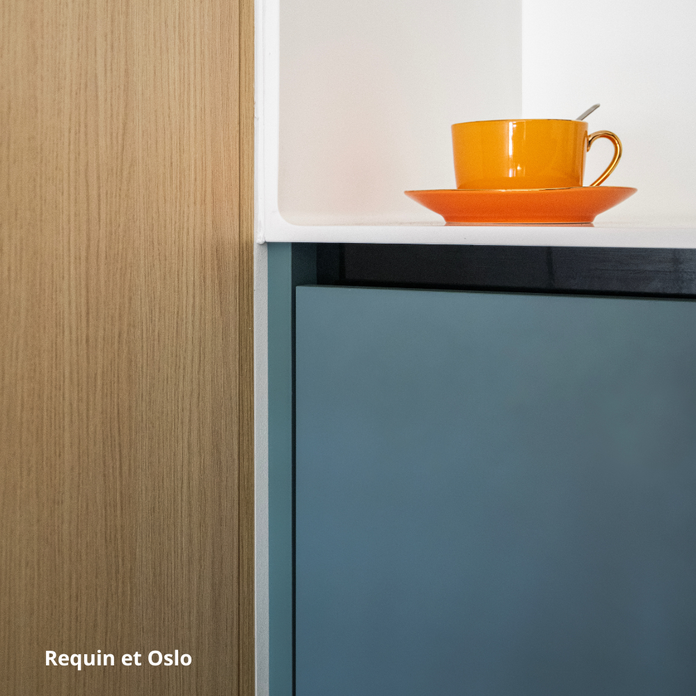 Focus sur des façades de cuisine bleu gris et aspect bois clair, et plan de travail blanc